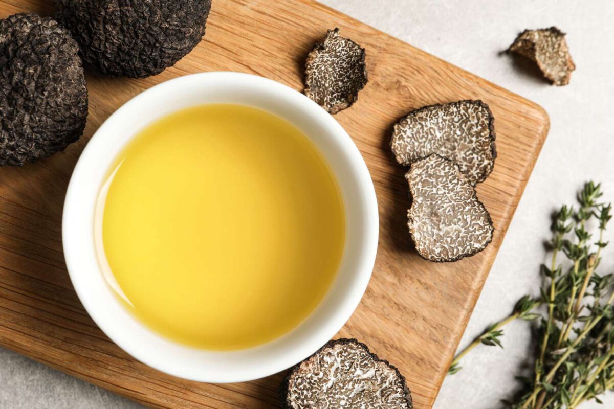 Fresh truffles, oil in bowl and thyme on light grey table