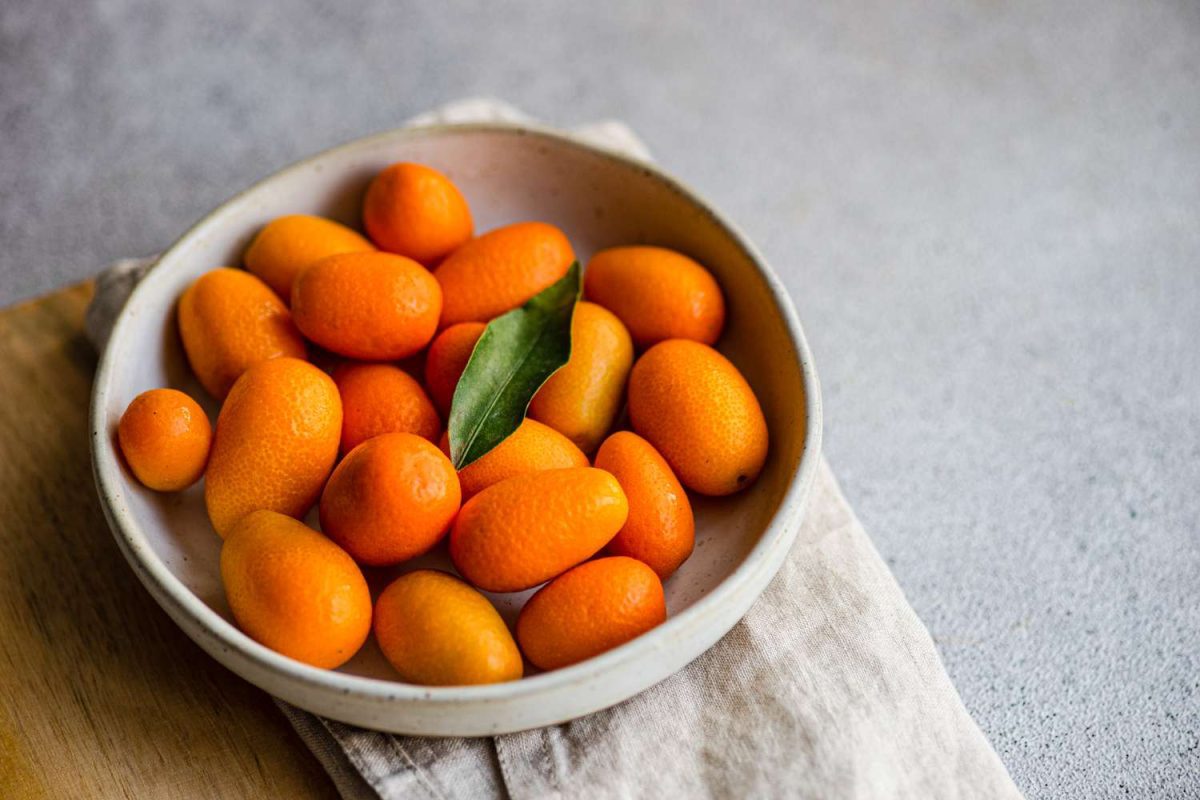 Organic ripe kumquat in the bowl on the concrete table