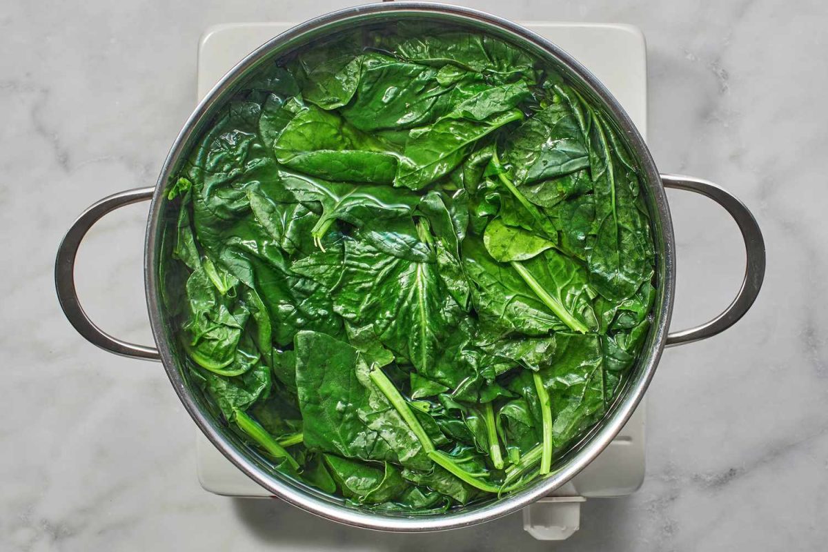 spinach in water in pot on burner
