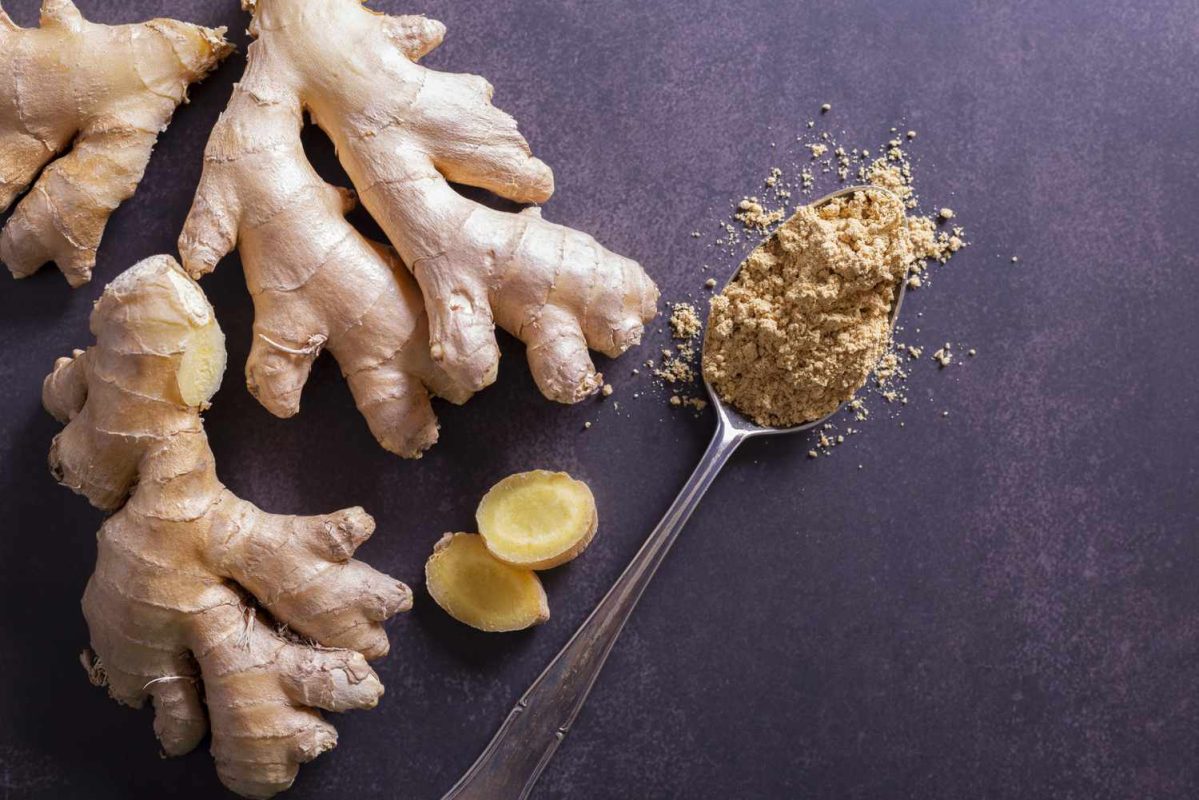 pieces of fresh ginger root and a spoon holding powdered ginger