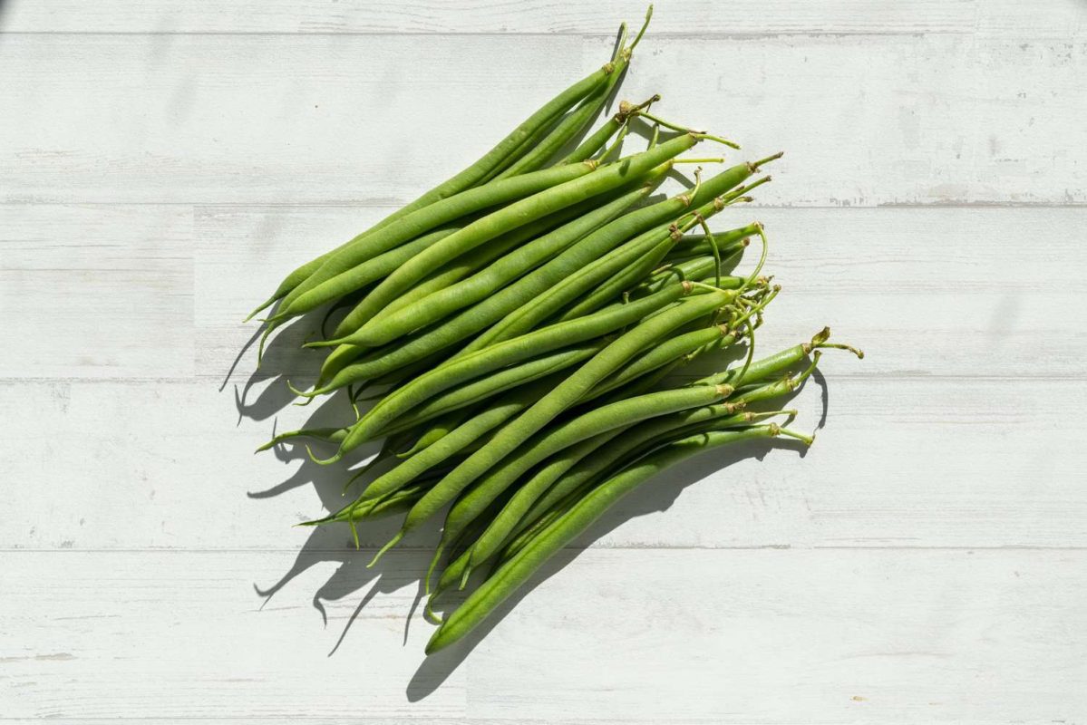 fresh green beans on white surface