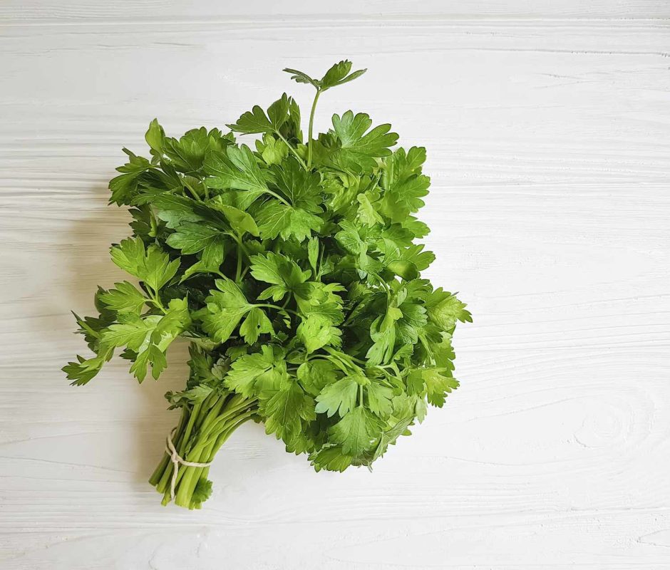 bunch of fresh parsley on white wooden surface