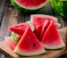 Slices of watermelon on a wooden cutting board with a knife beside them