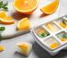 Ice cube tray with citrus slices and mint orange wedges on a marble surface