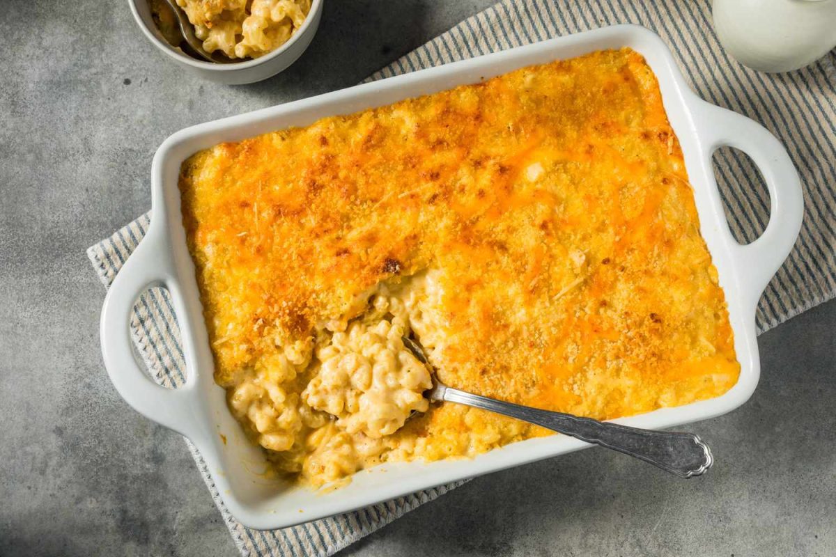 A baked macaroni and cheese dish with a serving spoon resting inside the pan