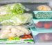 Stacked frozen food including vegetables in bags and containers arranged in a freezer
