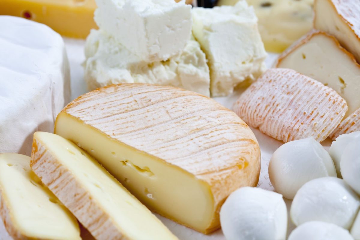 Assorted soft cheeses including sliced and whole varieties arranged on a surface